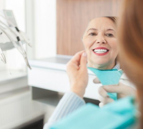 Woman looking at smile after one visit dental restoration