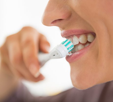 Woman with dental implants in Corpus Christi, TX brushing her teeth