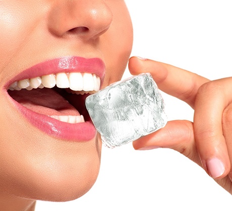 Woman with dental implants in Corpus Christi, TX biting an ice cube