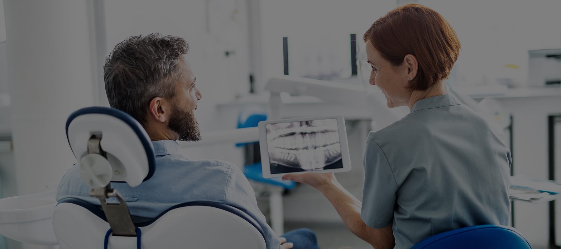 Man in dental chair talking to dentist and looking at digital x-rays