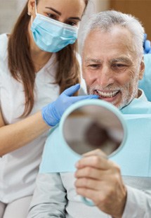 older man smiling in dental mirror