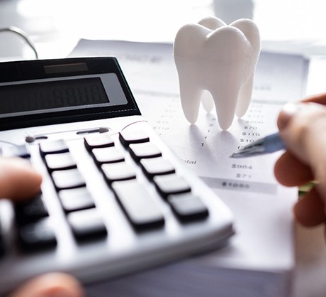A model tooth next to forms and a calculator
